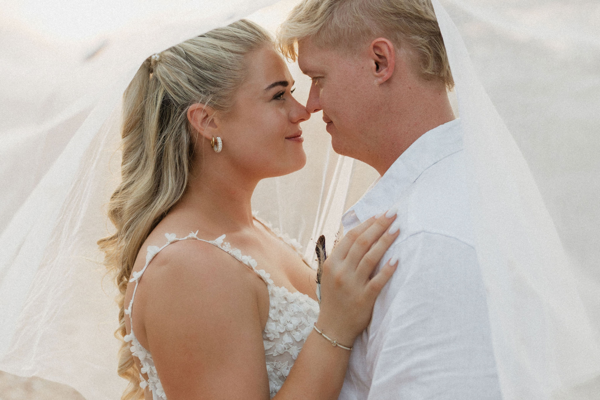 The bride and groom gazing at each other beneath a draped veil