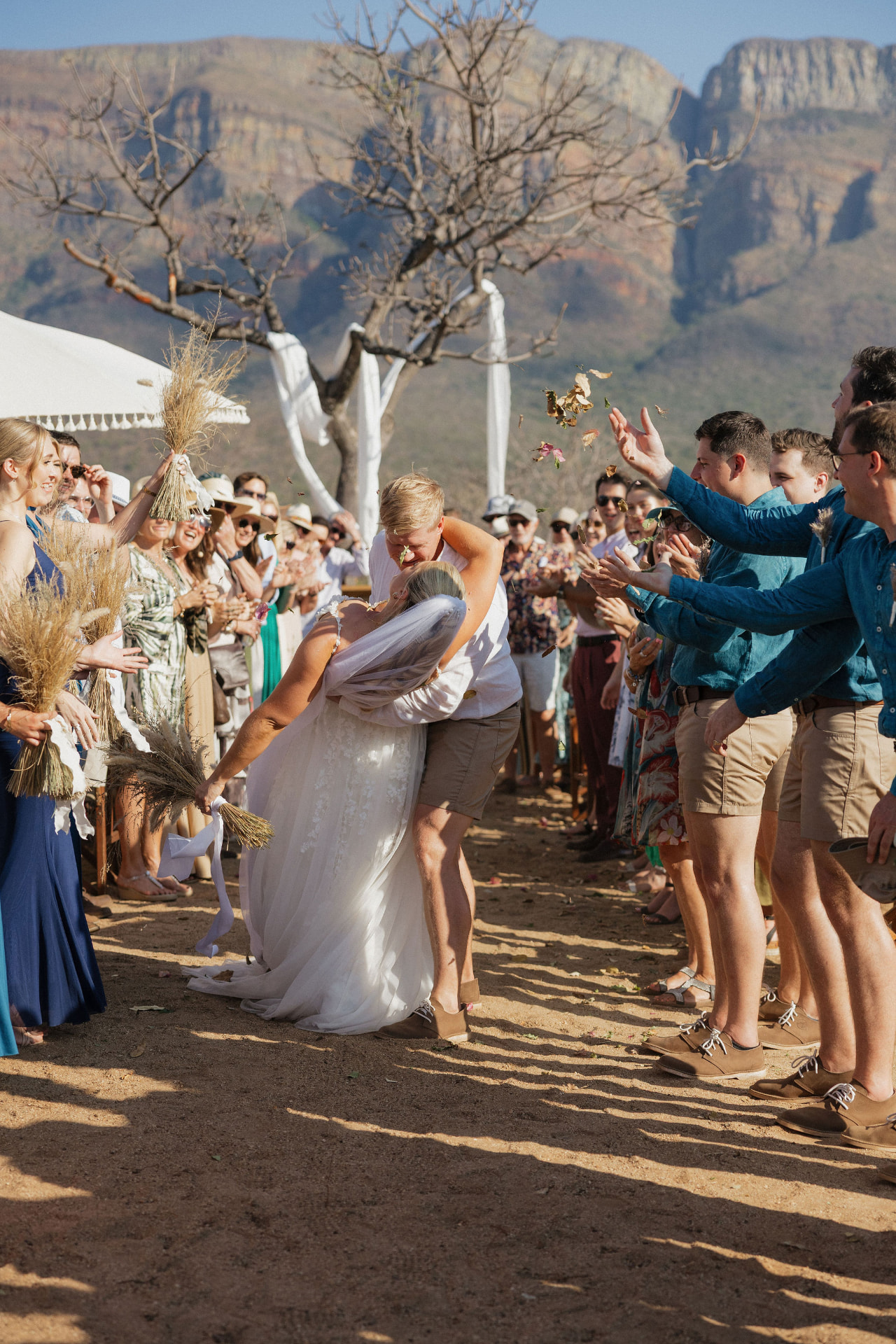 The newlyweds sharing a dip and kiss as guests toss leaves