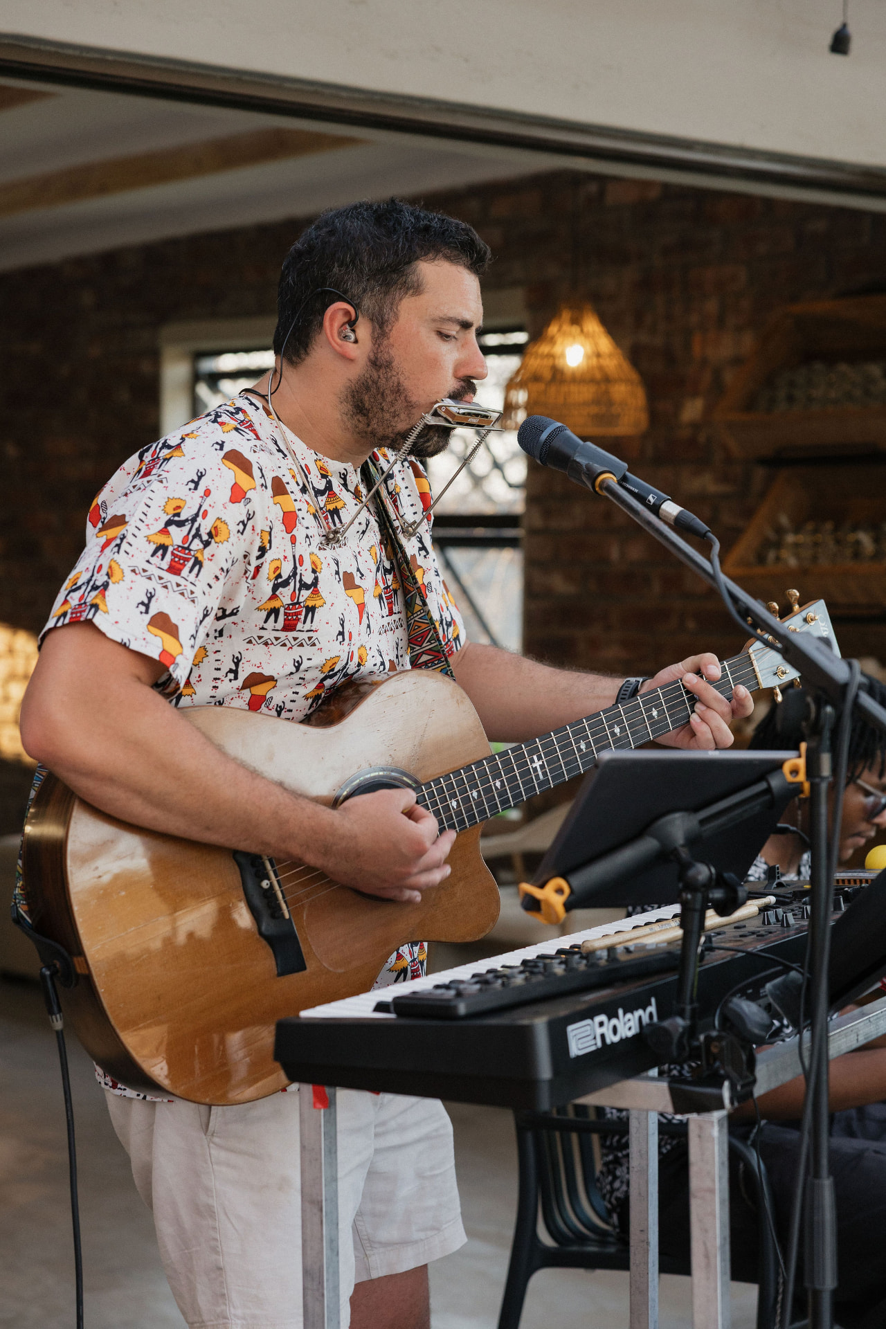 A musician playing guitar and harmonica during the reception