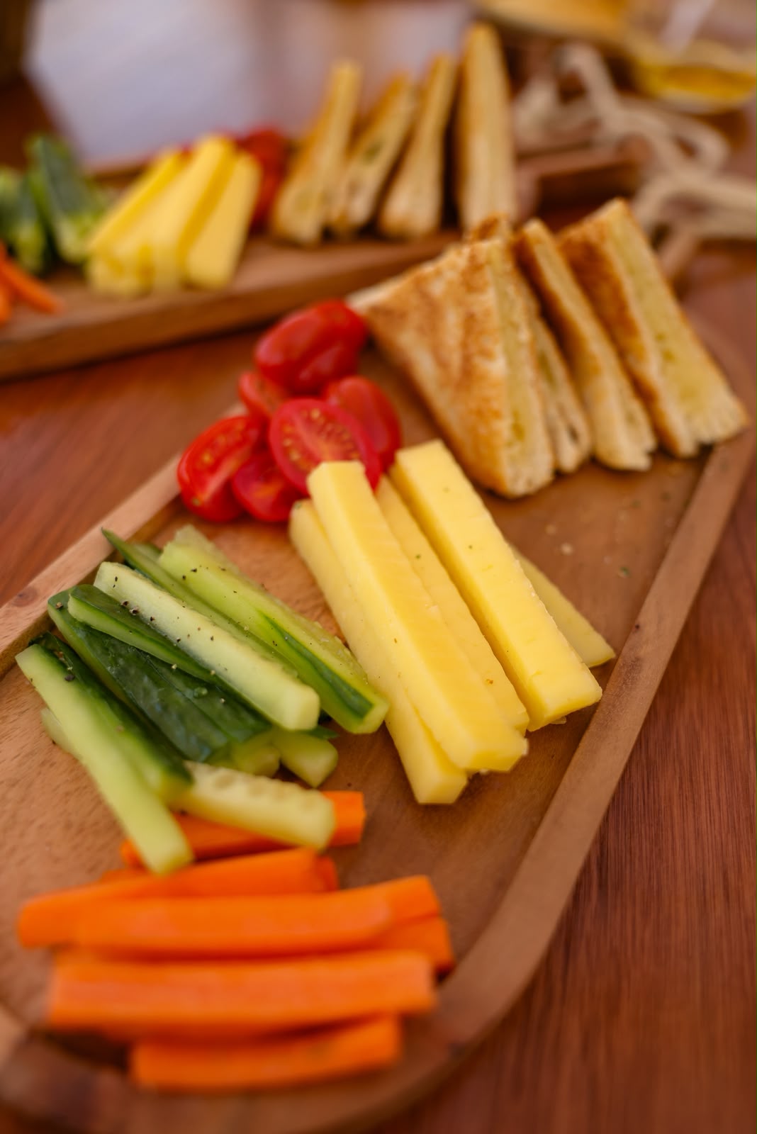 A snack platter with fresh vegetables, cheese sticks and toasted sandwiches