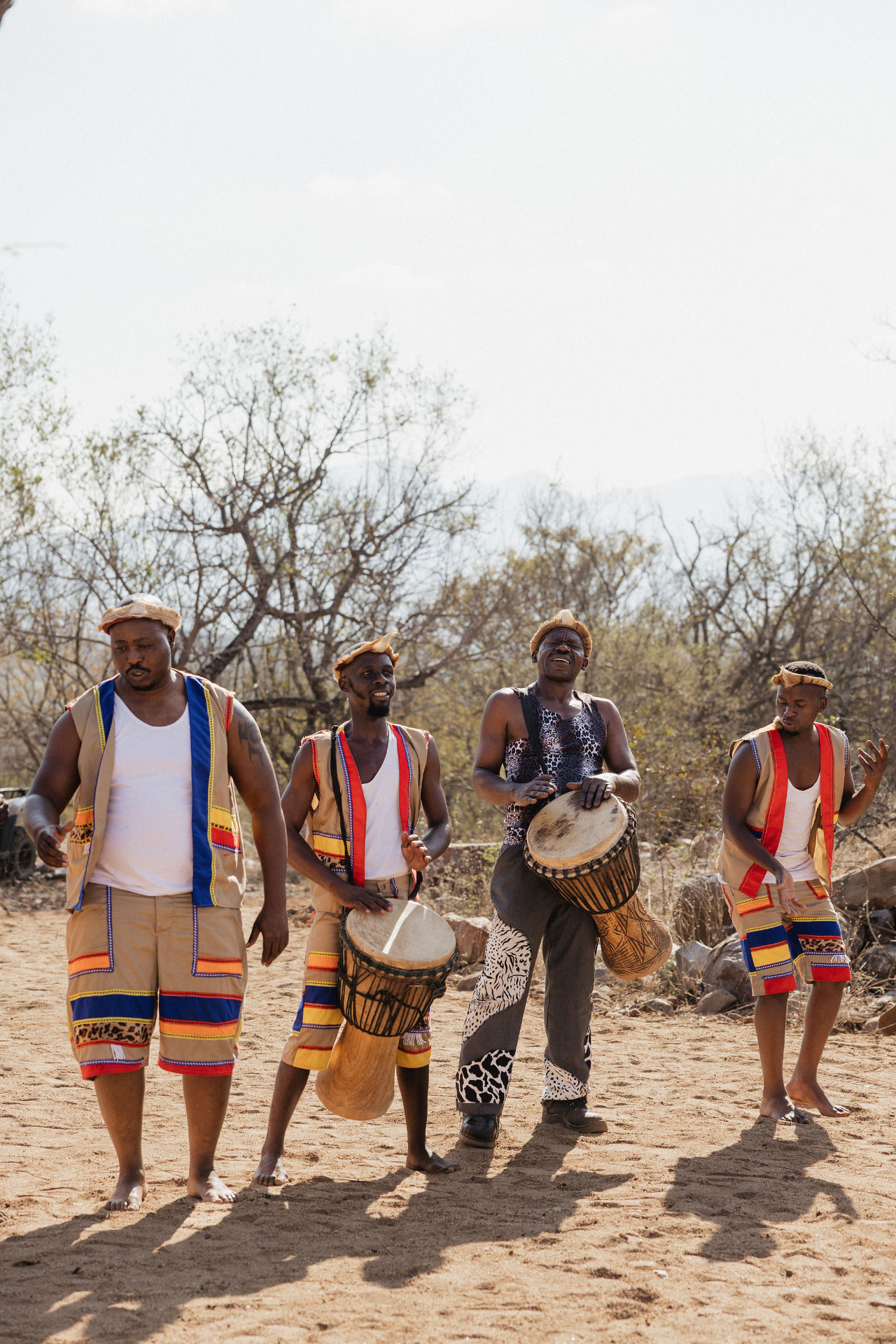 Djembe players in traditional attire performing in the bushveld