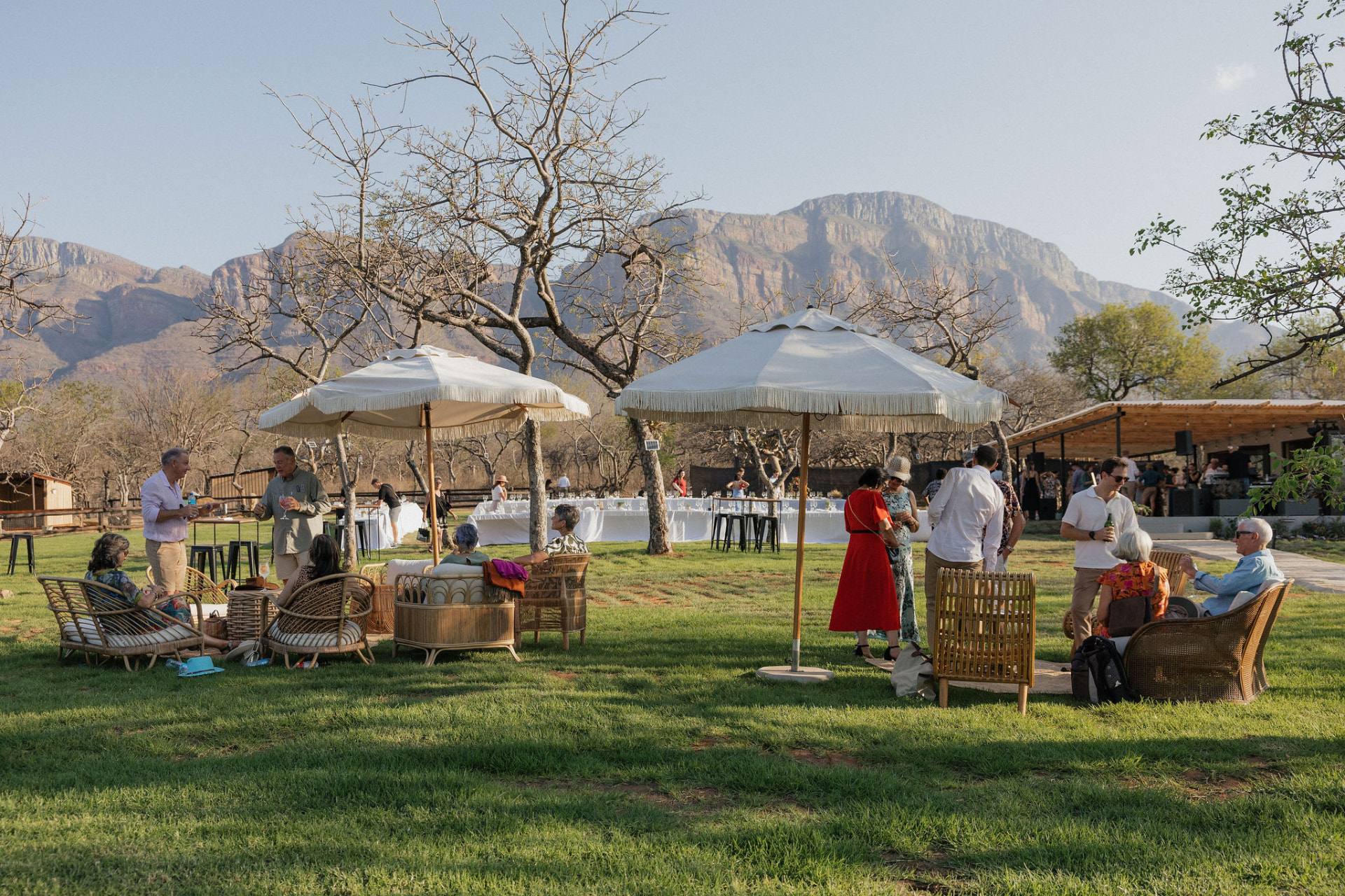 Guests relaxing under fringed umbrellas on the lawn